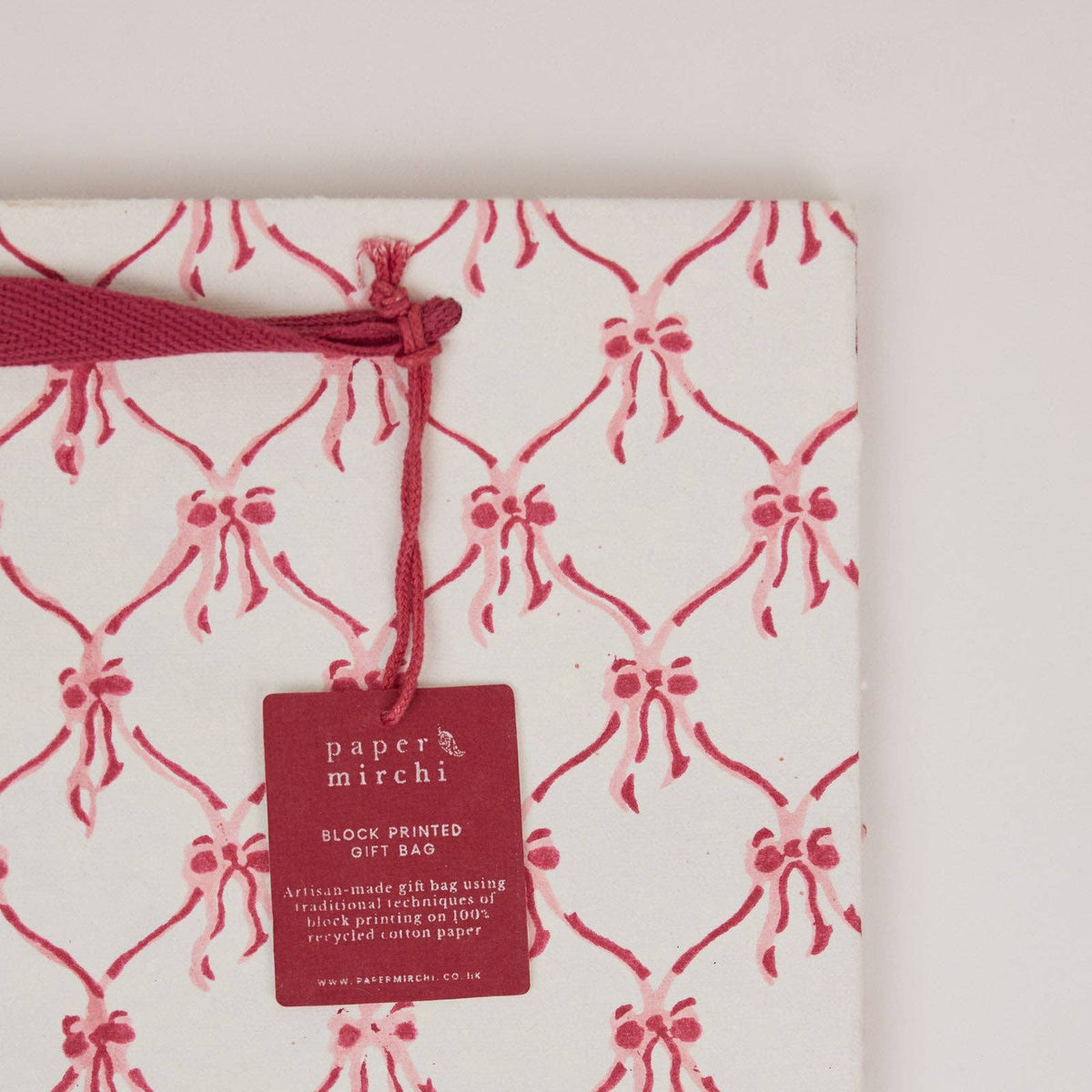 Close up of a Pink christmas bow design block printed gift bag by paper mirchi and penny black
