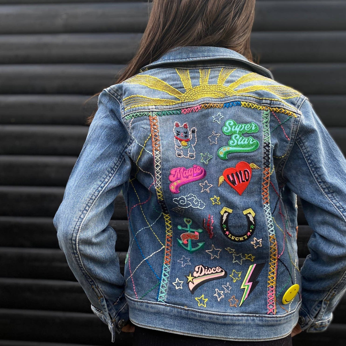 Colourful Iron on Patch - Artist by penny black showing back of denim jacket with lots of patches