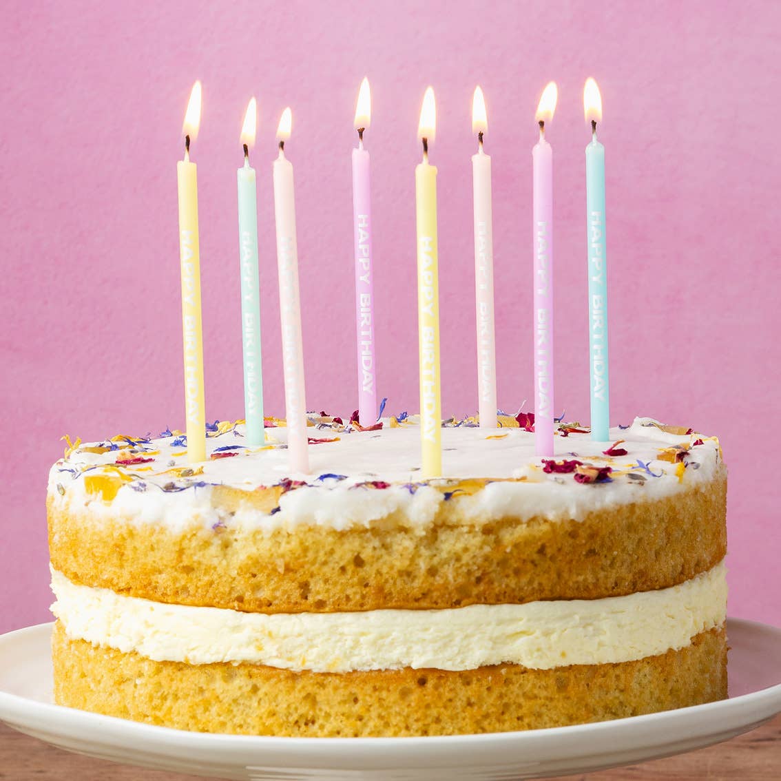 Pastel Happy Birthday Printed Candles 24pk shown lit on top of a birthday cake by penny black