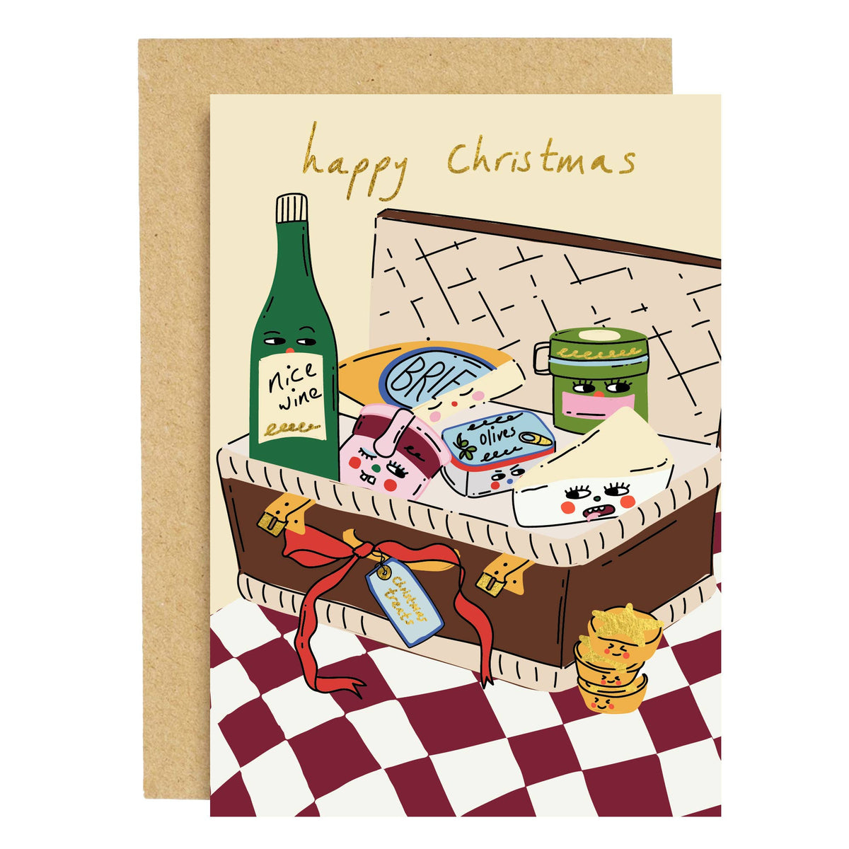 A Christmas greeting card with a kraft envelope, featuring a whimsical illustration of a Christmas food hamper with a green wine bottle, cheese, crackers, and olives under the text 'happy Christmas'.