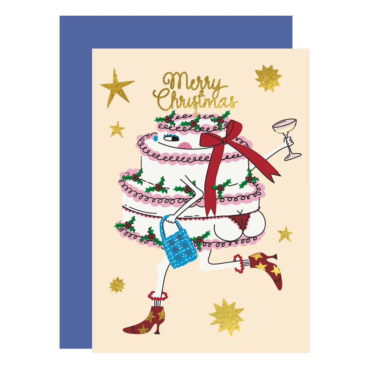 A Christmas greeting card featuring an illustration of a tiered cake with legs, a red bow, green holly accents, a blue handbag, and red high heels, with the words 'Merry Christmas' in gold script. The card is shown with a blue envelope behind it on a white background.