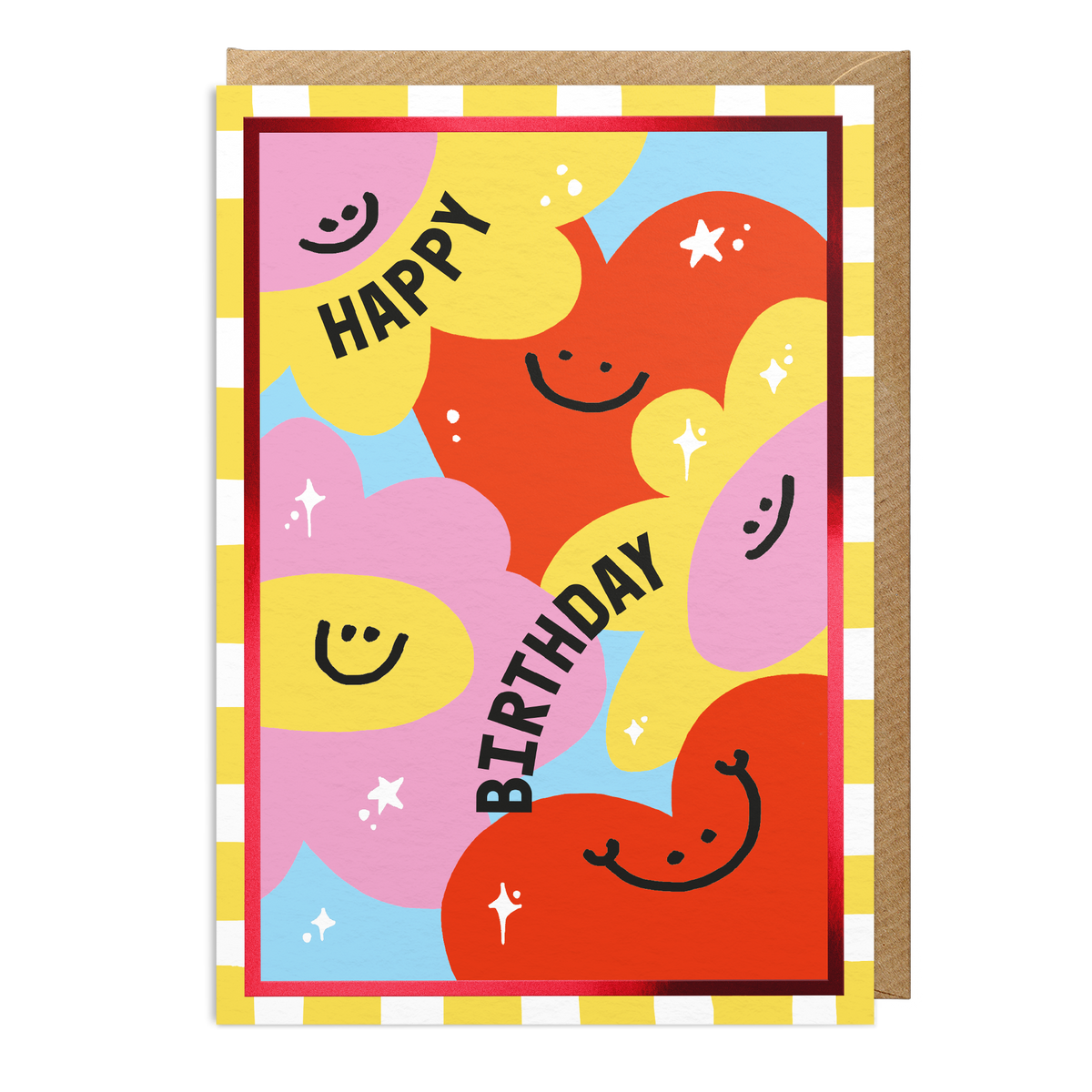 A colourful birthday greeting card with abstract heart and balloon shapes in pink, yellow and orange with black smiley faces and the words 'HAPPY BIRTHDAY' in black. A brown envelope is partially visible behind the card on a white background.