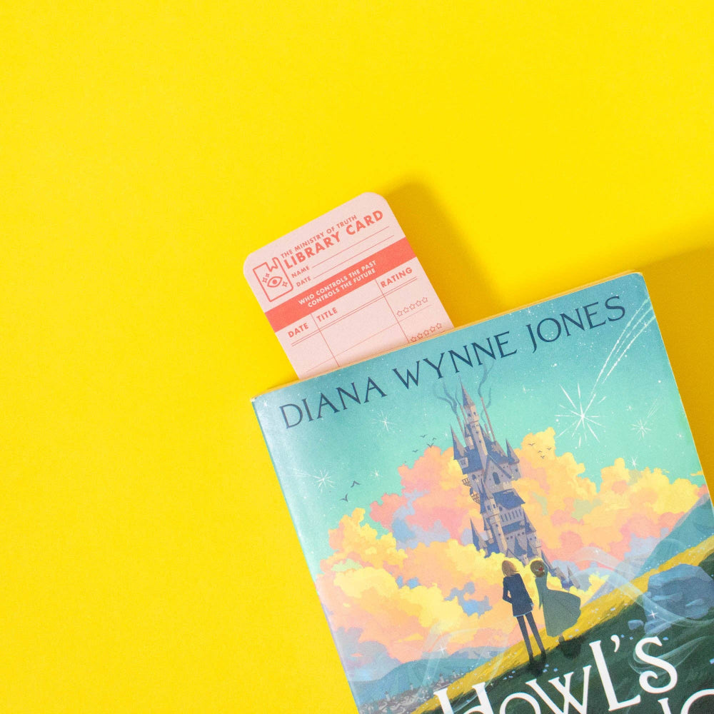 Book with a castle illustration on the cover and a library card bookmark on a yellow background