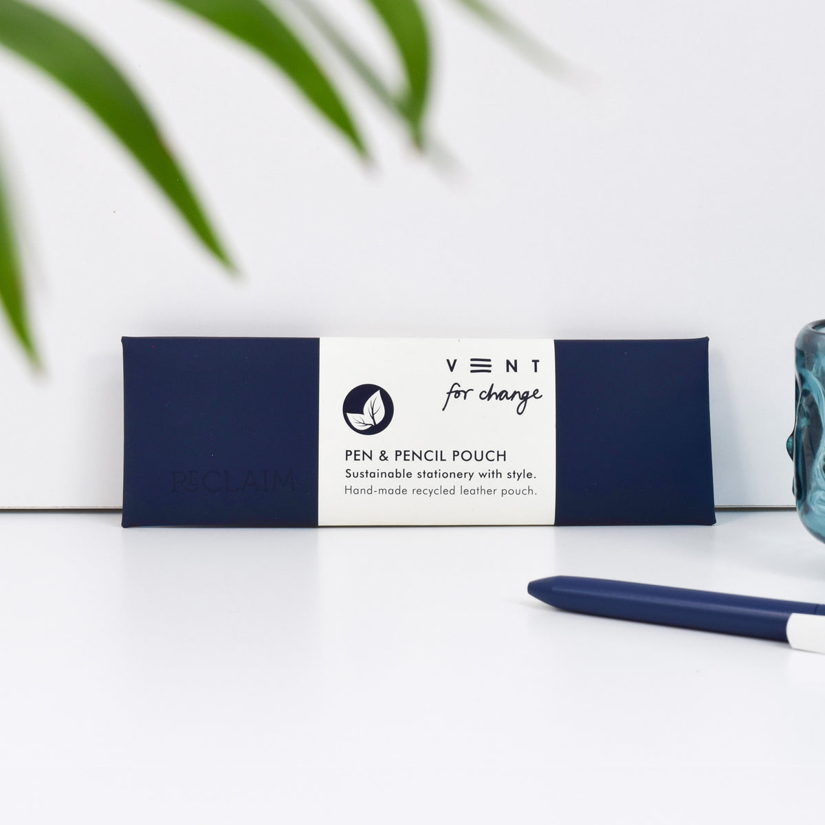 A navy blue pen and pencil pouch made of recycled leather and has the word 'Reclaim' embossed in it.