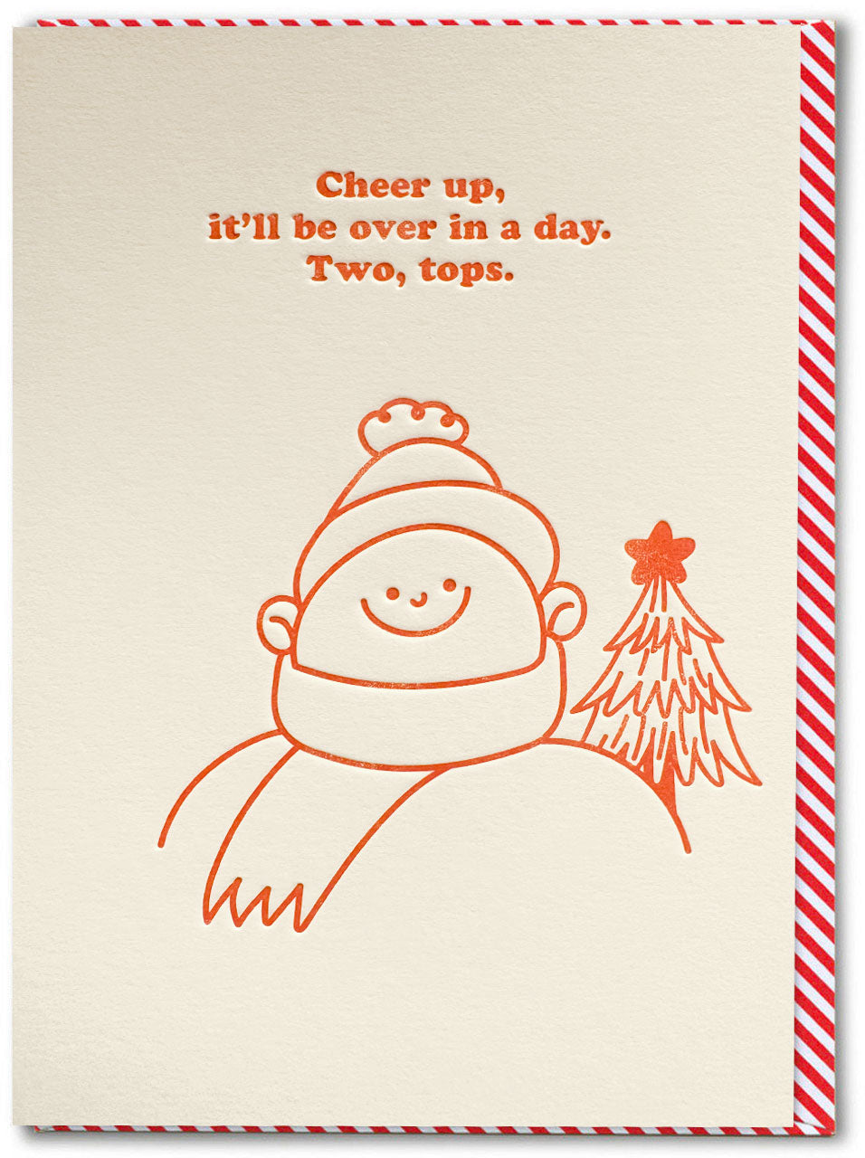 A christmas greeting card with a cream-coloured background and candy stripe envelope behind. The card features a simple illustration of a smiling person wearing a hat and scarf next to a small Christmas tree, with the text 'Cheer up, it'll be over in a day. Two, tops'.