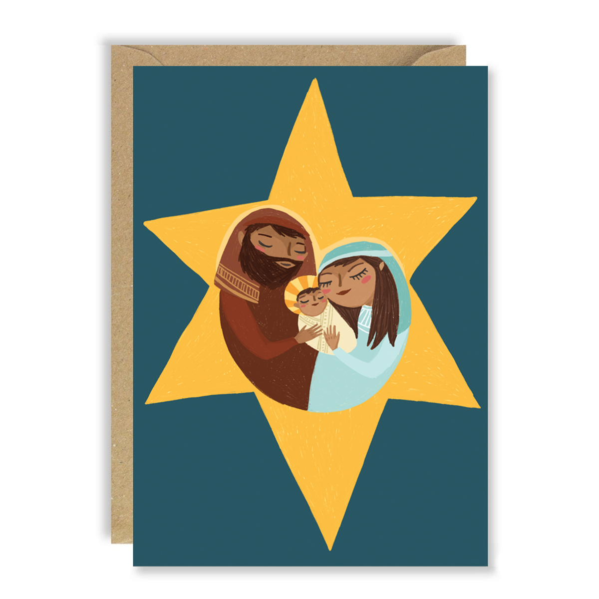 A Christmas greeting card with a kraft envelope behind it, featuring an illustration of Mary and Joseph hugging the baby jesus inside a large yellow star on a dark teal background.