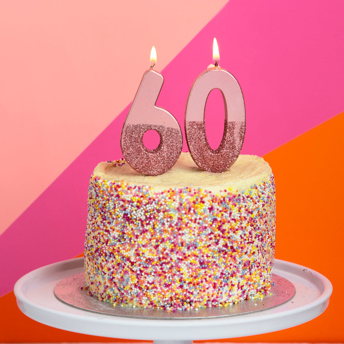 Rose Gold Glitter Number Candle by talking tables at penny black - 6 and 0 lit candles on a birthday cake covered in sprinkles.