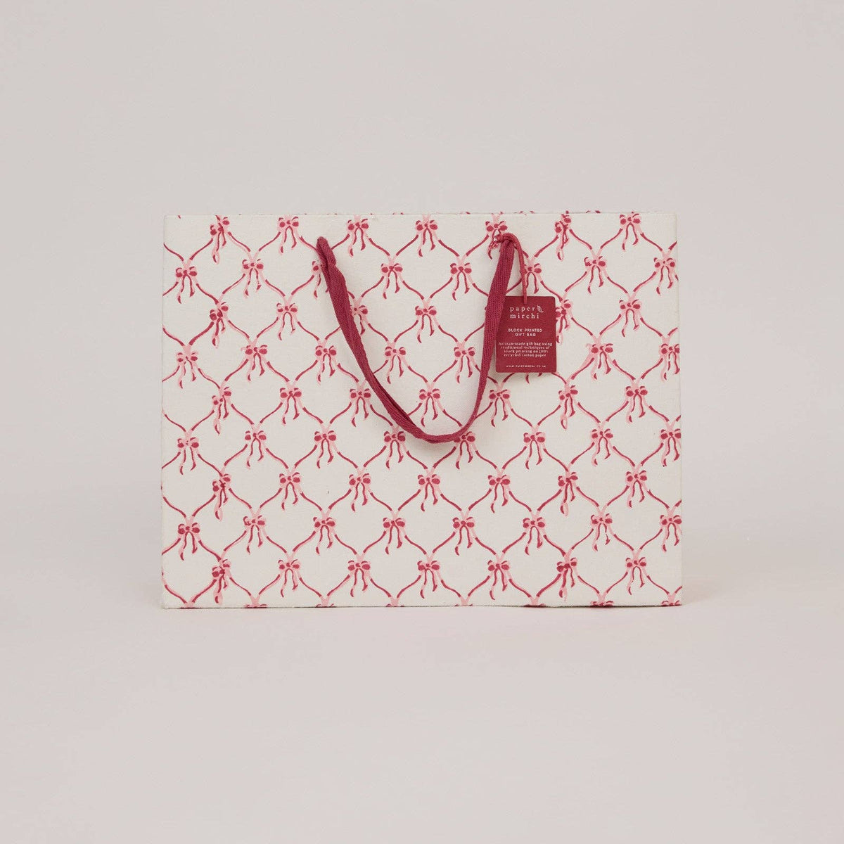 A large christmas gift bag with pink christmas bow design on a light gray background by paper mirchi at penny black