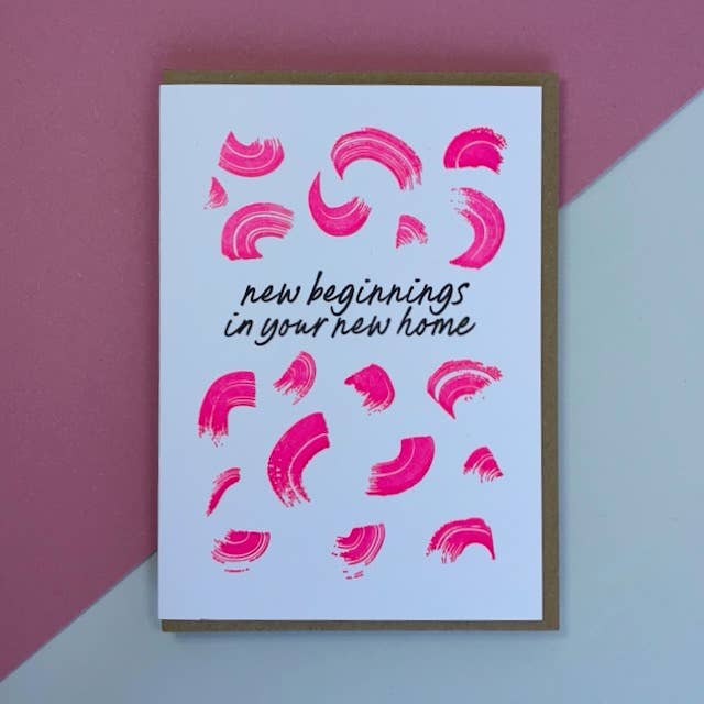 Letterpress new home card with pink abstract designs and black text 'new beginnings in your new home' on a cream background