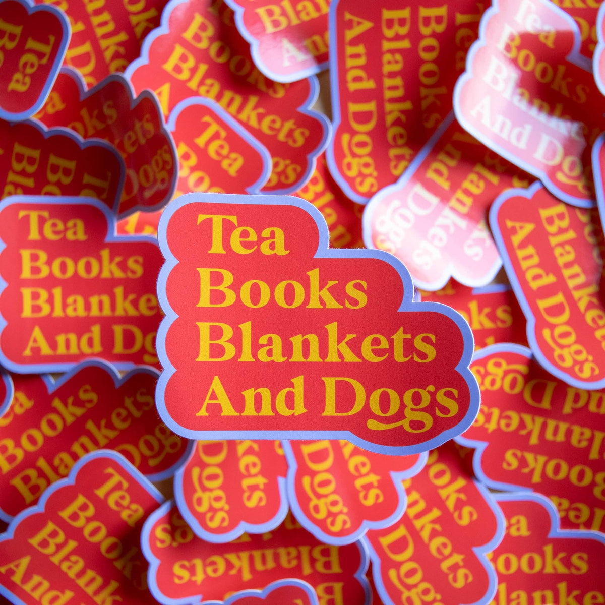 Stack of 'Tea Books Blankets And Dogs' stickers with red and yellow text.
