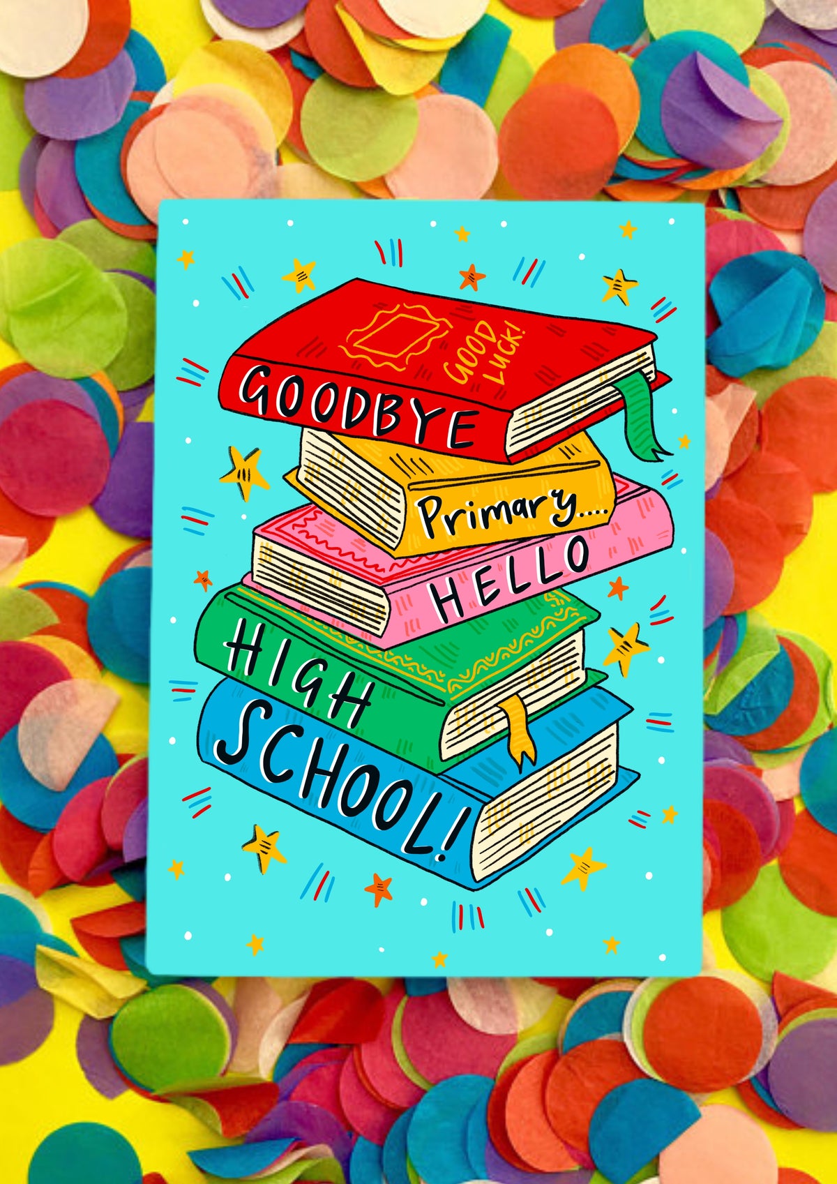 A greetings card with a white background covered in light blue squares like a jotter. The main image is a colourful jauntily stacked textbooks with the words 'Goodbye primary... hello high school!' - one word on each book. The card is lying on a bed of rainbow confetti.