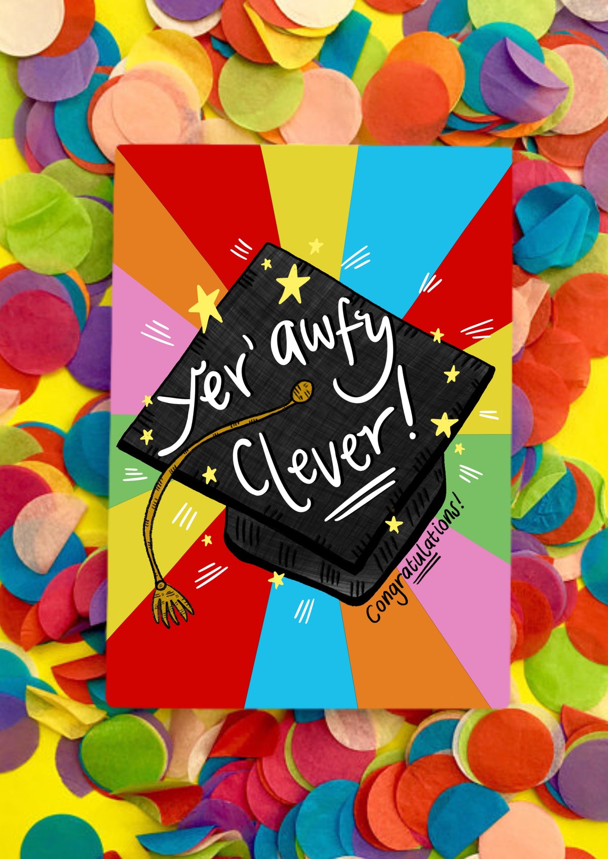 A greetings card with a rainbow sunbeam background and a black graduation cap in the middle. It has a gold tassel and white script writing saying 'yer awfy clever'! Underneath is also says 'congratulations'. The card is lying on a bed of rainbow confetti.