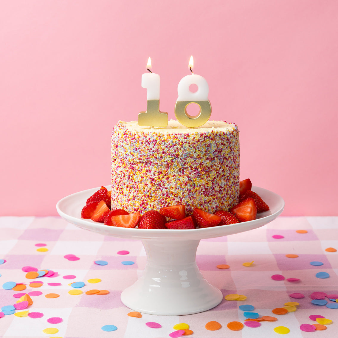 White & Gold Number Milestone Birthday Candle 18 set on top of a cake covered in sprinkles